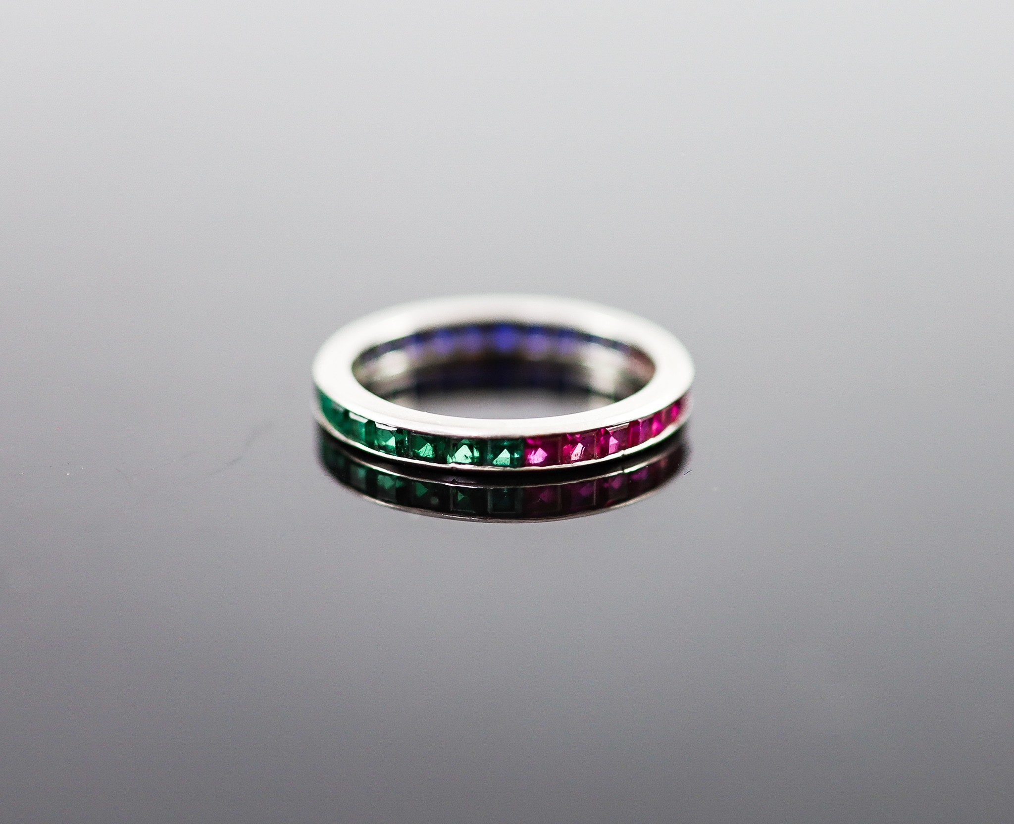 A platinum? ruby, emerald and sapphire set full eternity ring